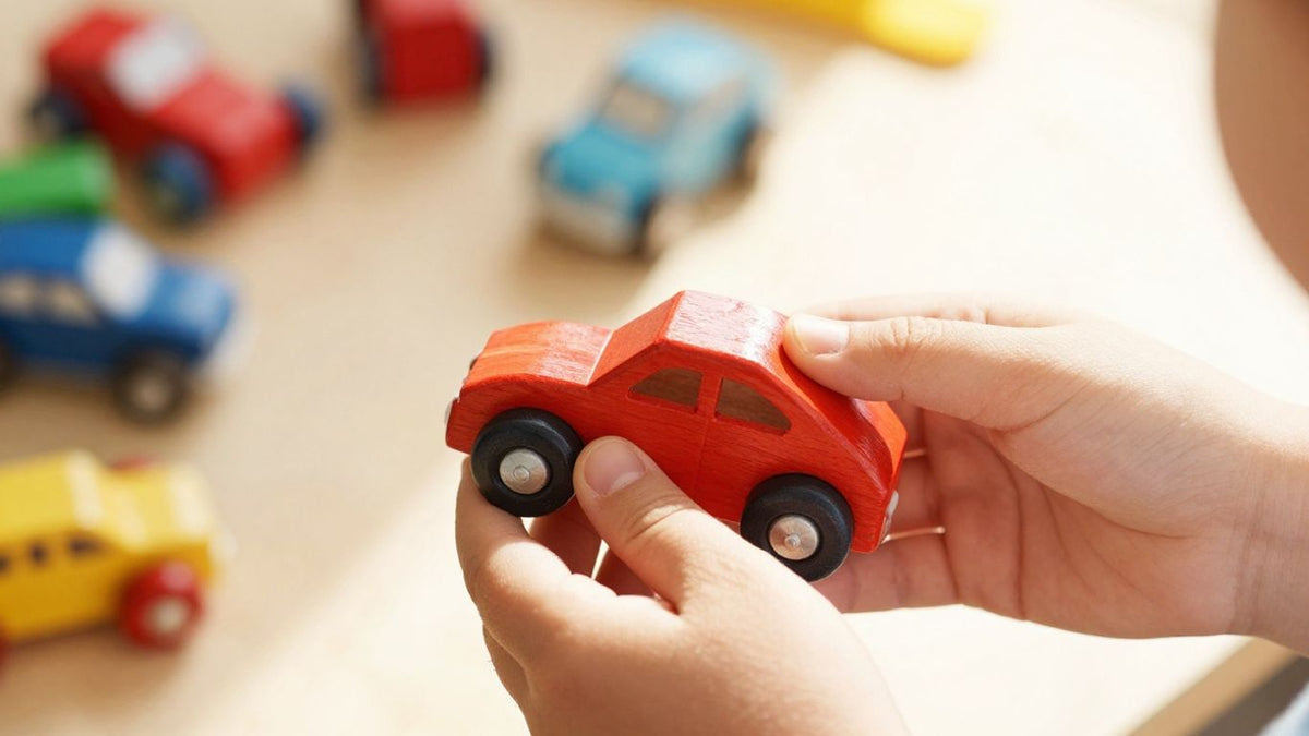 Child's hands holding a wooden toy car.